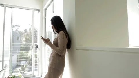 Pretty girl texting by large window 스톡 동영상 76733436