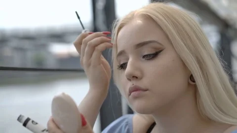 Pretty girl using mascara while sitting on the boat Stock Footage 85065528