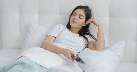 Pretty Girl using Smartphone in Bed Видео 103835720
