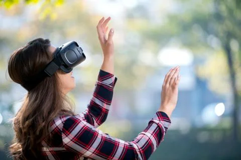 Pretty girl using VR headset outside in the park Stock Photos