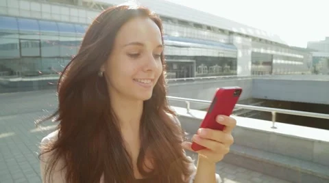 Pretty girl walking and using app on smartphone in the sun 動画素材 68386318