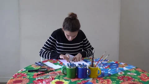 Pretty girl watches tutorial on cell phone to make origami card at art studio Vídeos de archivo 132291779