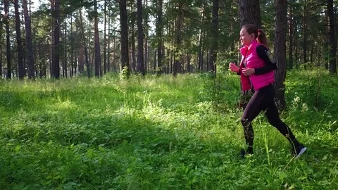 Pretty girl wearing sportswear and running in green forest at mountain during Stock Footage