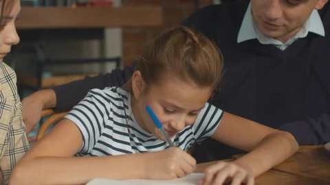 Pretty girl write something at lunch, parents sit with her and help Stock Footage 120800576