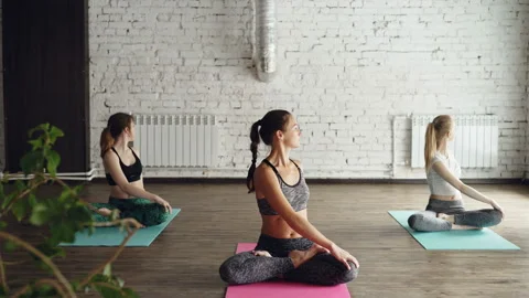 Pretty girls are doing yoga exercises under guidance of experienced instructor Stock Footage