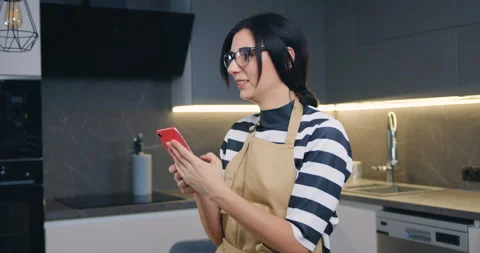 Pretty happy satisfied black-haired woman in glasses standing in the cozy Stock Footage 148867122