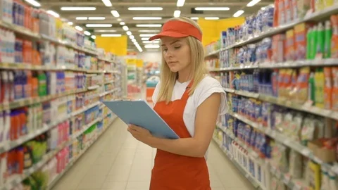 Pretty hardware store worker holding clipboard and standing among shelves in Stock Footage 107261109