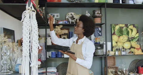 Pretty hardworking calm black-skinned woman accounting goods in souvenirs shop Stock Footage 143932431
