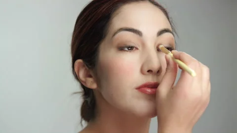 Pretty Hispanic brunette model applies eye shadow in repeated brush strokes Stock Footage 193908253