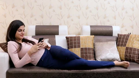 Pretty Indian female smiling while using her smartphone in trendy casual wear Stock Footage 135654422