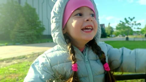 Pretty kid playing and smiling outside in a park. Happy little girl playing outs Stock Footage 280859636