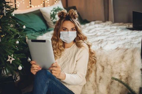 Pretty lady holding tablet while sitting on the floor in her bedroom Stock Photos