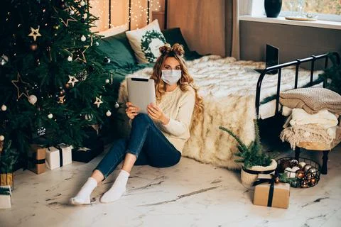 Pretty lady holding tablet while sitting on the floor in her bedroom 库存照片