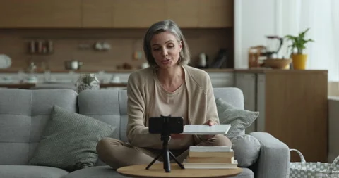 Pretty literature blogger presenting stack of bestsellers to blog audience Stock Footage 240078214