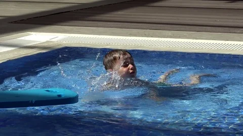 Pretty little boy is playing in the pool Stock Footage 80571200