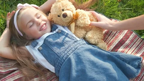 Young girl hugging teddy bear, eyes closed, Stock image