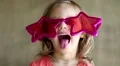 Pretty little girl in big glasses in the shape of stars looks at the camera HD Footage