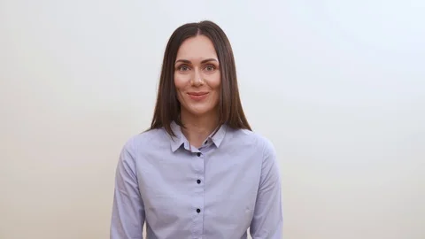 A pretty long-haired brunette looking into the camera, smiles, pushes up her Stock Footage 100058933