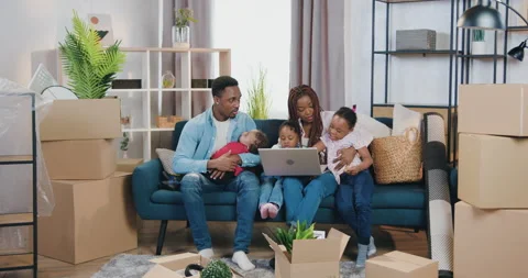Pretty loving smiling black-skinned mother with dreadlocks sitting on the sofa Stock Footage 150659512