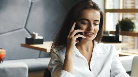Pretty manager using telephone sitting in cafe with laptop Stock Footage 117132273