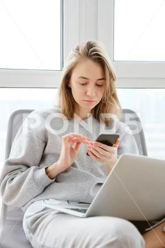 Pretty mid age woman using gadgets while sitting near the window Stock Photos
