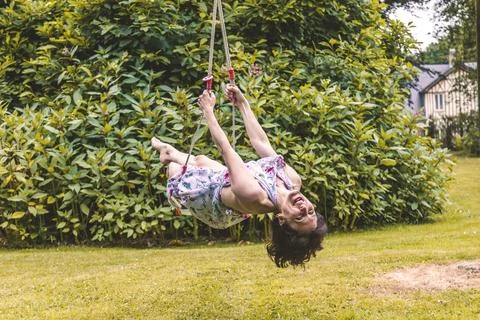 Pretty middle aged dark haired woman swinging on childrens swings Foto stock