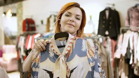 Pretty middle aged short haired woman is posing to the camera at clothing store Stock-Footage 127918929