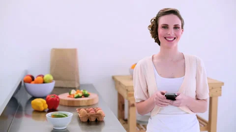 Pretty model standing in kitchen talking on the phone Stock Footage 29399982