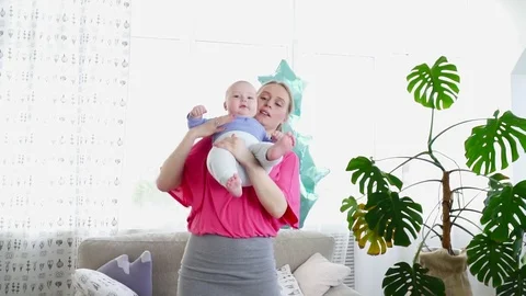 Pretty mother playing with her 6 months son in the room Stock Footage 75019042