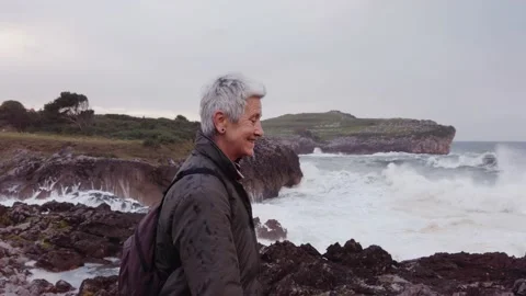 Pretty old lady with backpack strolling through a field Video stock 143640676