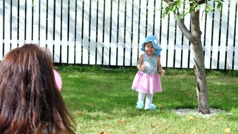 A pretty one-year-old girl in a hat from the sun and a gorgeous dress, goes Stock Footage 80442966