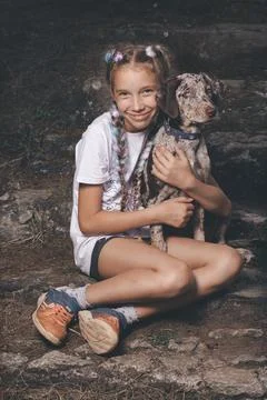 Pretty pigtailed young lady posing with her dog friend on stone stairs Stock Photos