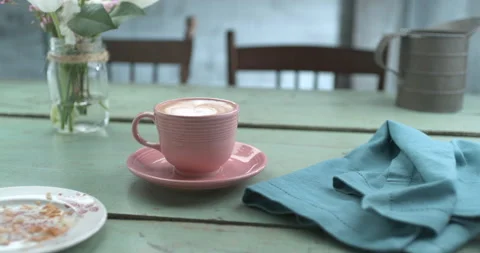Pretty pink latte cup next to empty plate of eaten croissant and napkin ultra sl Stock Footage 199460438