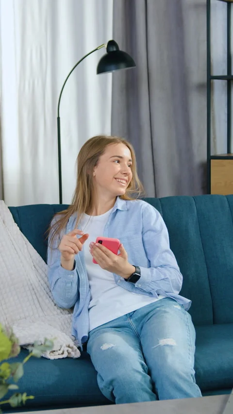 Pretty positive in high spirits young modern girl in casual wear sitting on comf Stock Footage 331432580