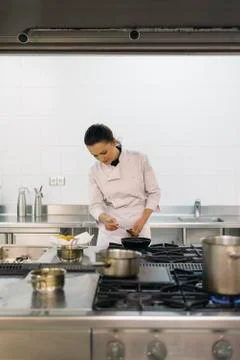 Pretty professional chef cooking in a kitchen. Stock Photos