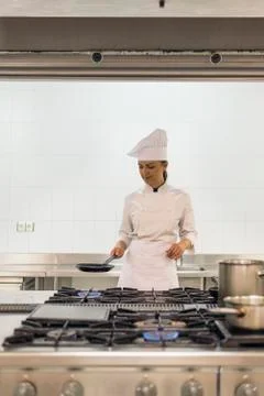 Pretty professional chef cooking in a kitchen. Stock Photos