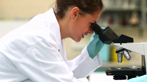 Pretty science student looking through microscope Stock Footage