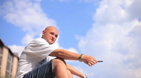 Pretty Serious Guy Sits on a Background of Clouds and Think About Something Stock Footage 66692171
