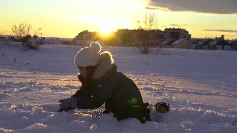 Pretty short haired girl throwing snowball to camera with amazing sunset as b Stock Footage 146420190