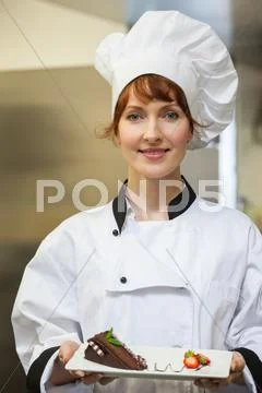 Pretty smiling chef presenting chocolate cake with strawberries Stock Photos