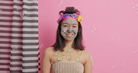 Pretty smiling eastern woman has gentle look at camera applies nourishing clay Stock Footage 147994231