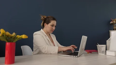 Pretty smiling lady in white jacket types on modern laptop Stock Footage 112385386