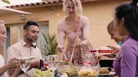 Pretty smiling middle-aged Caucasian woman putting a plate with food on the Stock Footage 200922972