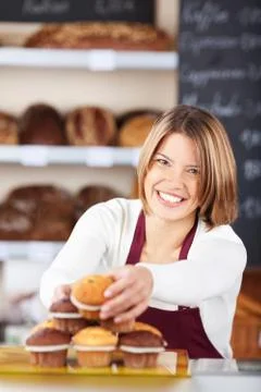 Pretty smiling worker selecting muffins Foto stock