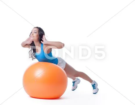 Pretty sportswoman exercising with orange ball Stock Photos
