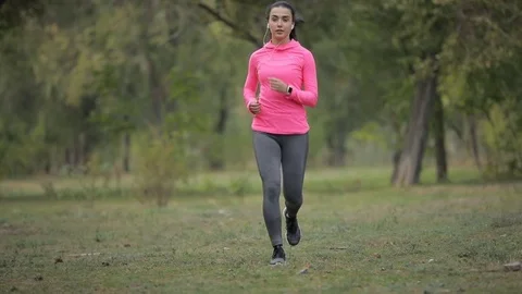 Pretty sportswoman in pink sportswear jogging outdoors, healthy lifestyle Stock Footage
