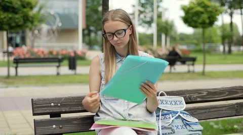 Pretty student sitting on the bench and looking on her papers 스톡 동영상 67369201