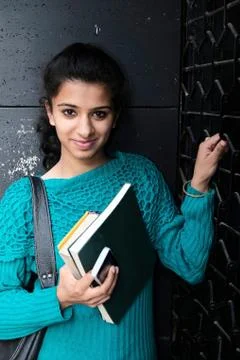 Pretty student smiling with books against a wall Stock Photos