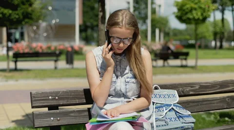 Pretty student talking on cellphone and looking on her homework Stock-Footage 67369234