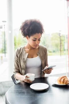 Pretty student using her phone in cafe 스톡 사진